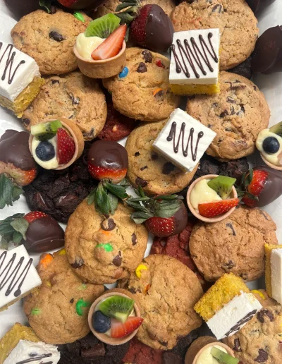 Dessert platter with cookies, chocolate-covered strawberries, fruit tarts, and cake bites