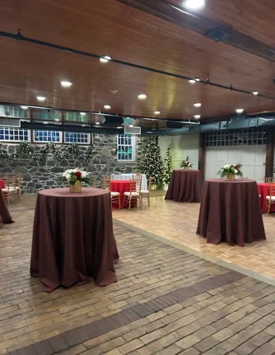 Holiday cocktail reception setup inside Rockwood Carriage House with high-top tables, stone walls, and Christmas decor