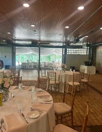 Wedding reception setup at Rockwood Carriage House with round tables, gold chairs, blush linens, and garden views