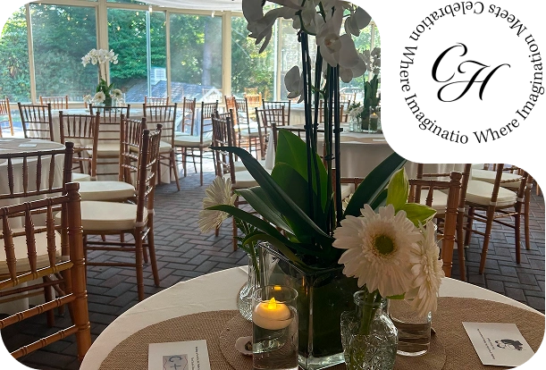 Wedding reception table centerpiece with white orchids, daisies, candlelight, and garden views at Rockwood Carriage House