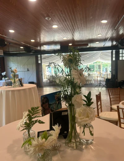 White floral cocktail table arrangement at Rockwood Carriage House with framed photo and reception space in the background