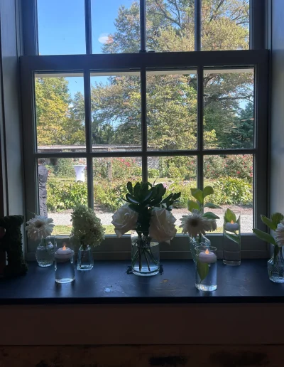 Window display with flowers and candles overlooking the gardens at Rockwood Carriage House