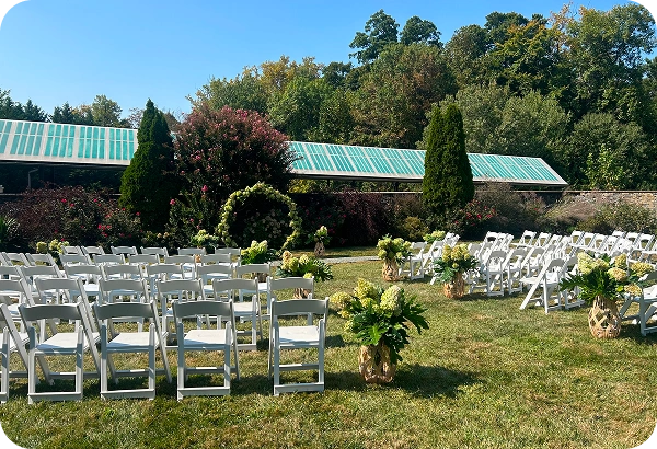 Outdoor wedding ceremony setup at Rockwood Carriage House with white chairs, floral aisle arrangements, and garden arch