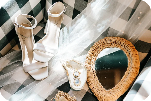 Bridal details with white wedding shoes, veil, jewelry, and wicker mirror